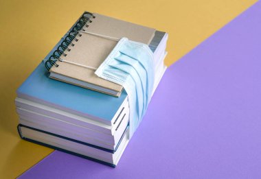 Yüz maskesi takılı kitaplar. Coronavirus konsepti sırasında okula dönmek.