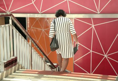 Sapan çantalı bir kadının merdivenlerden aşağı inişi.