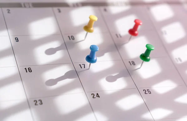 Thumbtacks pin on calendar. Concept for busy schedule.