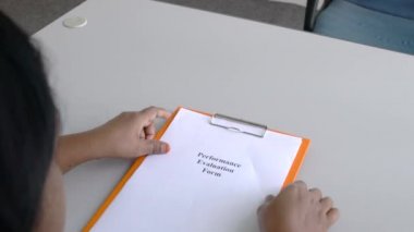 İş kadını elinde kelimelerle bir dosya panosu tutuyor. Performans Değerlendirme Formu kağıda basılmış. Ofis ayarları.