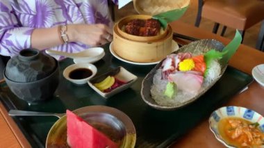 Japon mutfağı yemekleri, pirinçli sashimi tabağı, salata ve meyveler. Lokantada bir masada servis edildi..