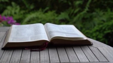 Bahçedeki masada kutsal kitap açık ve sayfalar rüzgar estiği için ters dönüyor. Din ve inanç kavramı