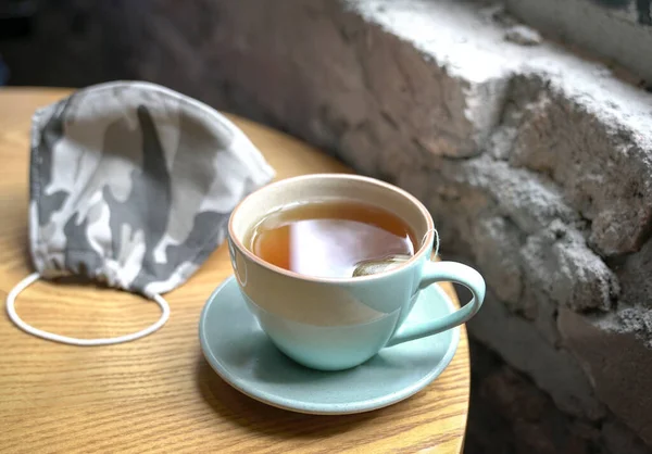 Cup Hot Tea Face Mask Wood Table Cafe — Stock Photo, Image