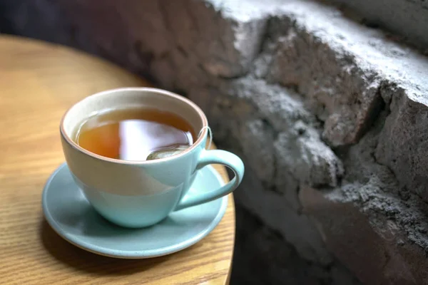 窓の横の木のテーブルに熱いお茶のカップ — ストック写真