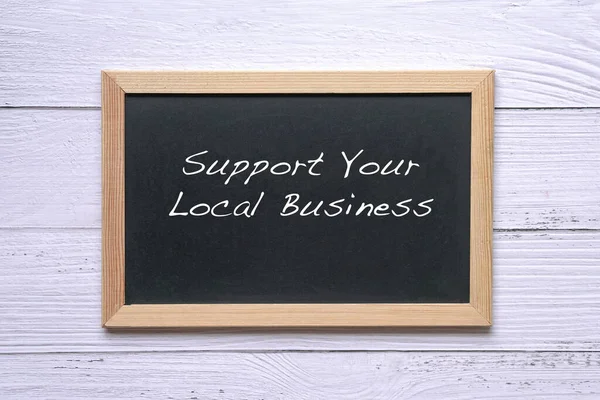 Support Your Local Business, words written on blackboard. Reminder to support and buy goods and services in your community.