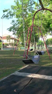 Parktaki boş oyun parkının dikey videosu. Yavaşça sallan..