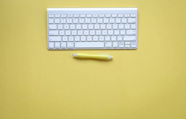 Bilgisayar klavyesi ve sarı kalemi olan sarı ofis masası. Üst Manzara. Boşluğu kopyala.