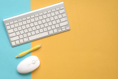 Sarı ve mavi arka planda klavye, fare ve sarı kalem. Üst Manzara. Boşluğu kopyala.
