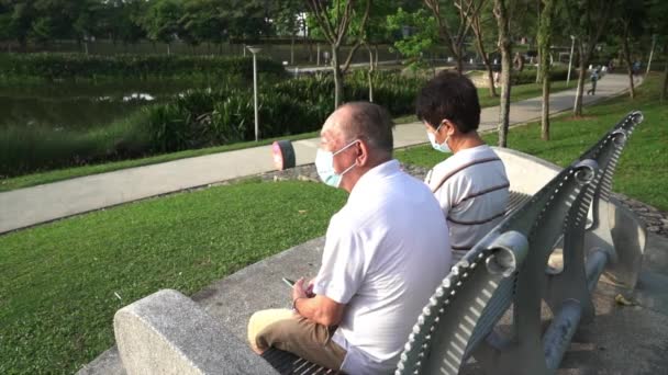 Yüz Maskesi Takıp Bankta Oturan Yaşlı Emekli Asyalı Bir Çiftin — Stok video