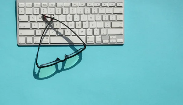 White Keyboard Reading Glasses Blue Background Top Copy Space — Stock Photo, Image