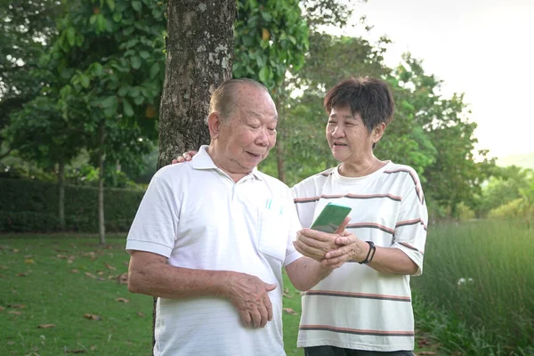 Happy Senior Asian Couple Smiling Talking Looking Phone Park — Stock Photo, Image