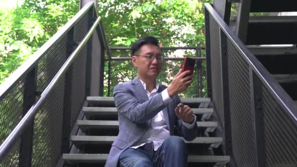 Бізнесмен Сидячи Сходах Посміхаючись Маючи Відеочат Використовуючи Свій Смартфон — стокове відео
