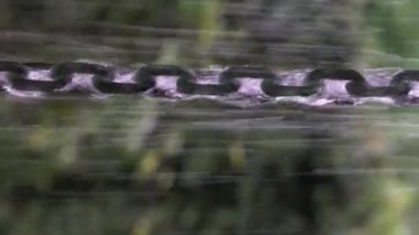 Sallanan metal zincirlere yağmur suyu çarpmış. Kapatın. Yavaş çekim. 