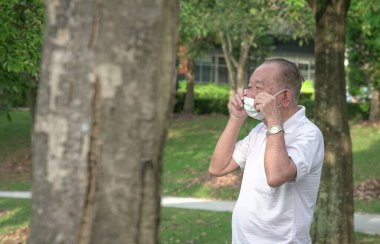 Kıdemli Asyalı adam dışarıdayken yüz maskesi takıyor. Koronavirüs salgınına karşı savaş.