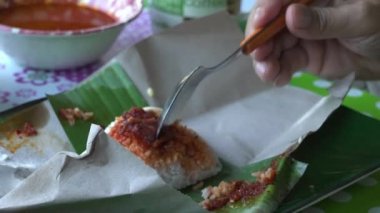 Nasi lemak paketini yiyen adam ya da hindistan cevizi sütüyle pişirilmiş Malezya kokulu pilav yiyen adam..