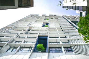 Şehirdeki ağaçları olan yüksek binalar. Düşük açı, yukarı bakıyor. Gökyüzü arkaplanı.