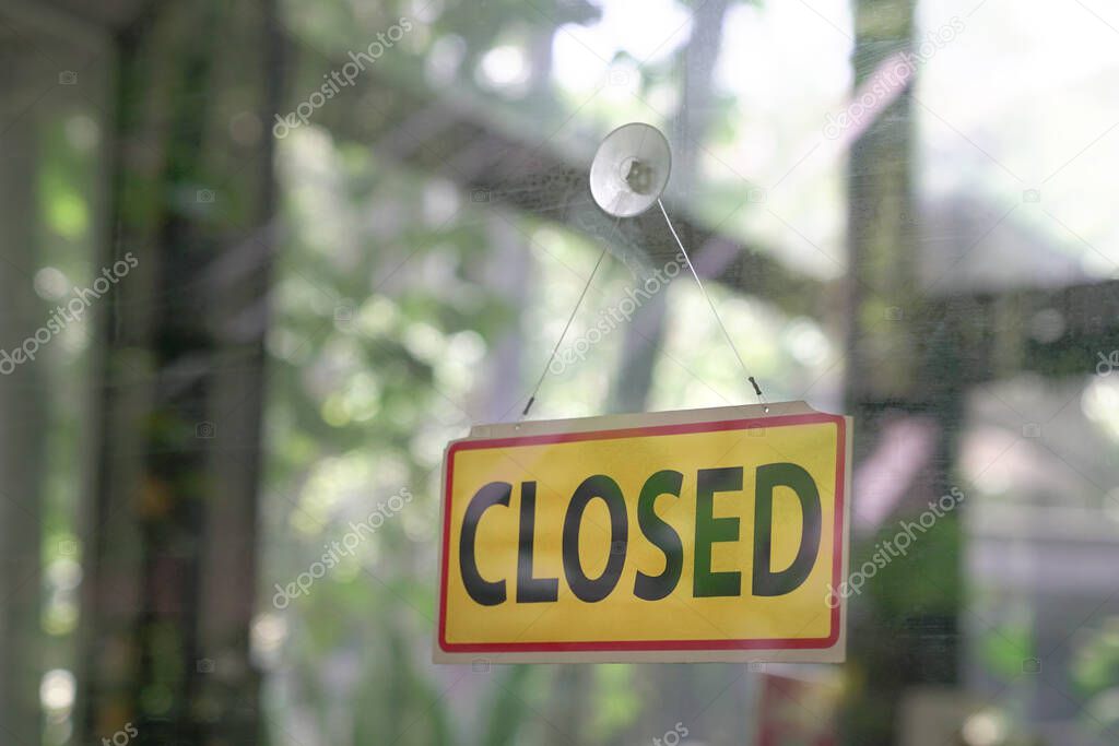 Closed signboard hanging on glass door of a restaurant. Copy space.