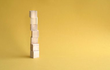 7 harf boş ve tahta blok üst üste yığılmış, sarı arkaplan. Boşluğu kopyala.