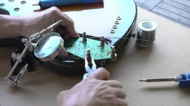 Gitar devresi tamir eden, kerpetenle fındığı beceren bir adam. DIY Evinde.