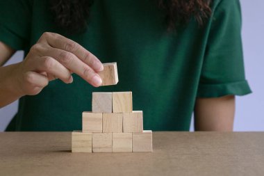 Ahşap blokları merdiven gibi dizen bir kadın. İş büyümesi veya başarı kavramı.