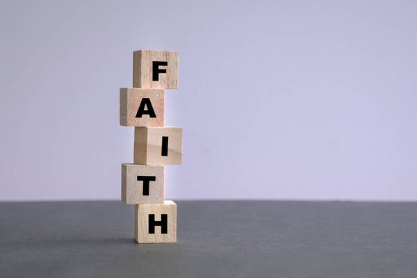 Слово "вера" написано на деревянных кубиках. Белый фон и серый цвет стола.
