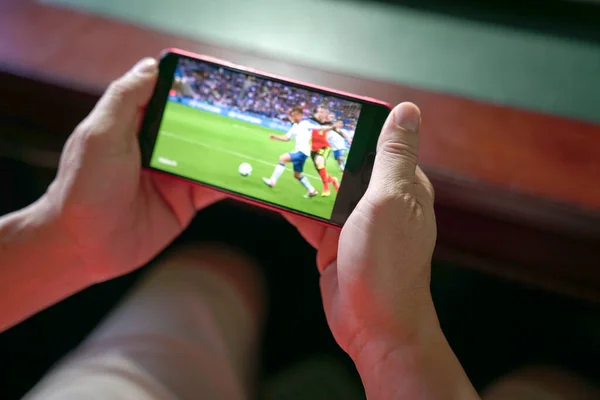 Man watching football and sport stream on mobile phone. Close up view. Home entertainment concept.