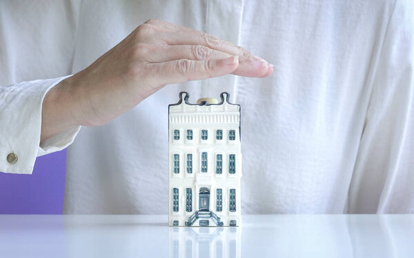 House apartment miniature covered by hand. Property insurance concept.
