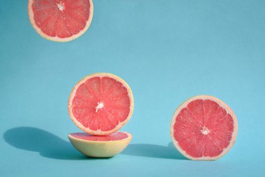 Güneş ışığında taze kesilmiş greyfurt ve mavi pastel arka planda sert gölgeler. Boşluğu kopyala.