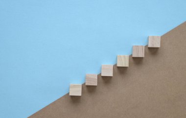 Wood block stacking as step stair. On blue and brown background. Business concept for growth success process.