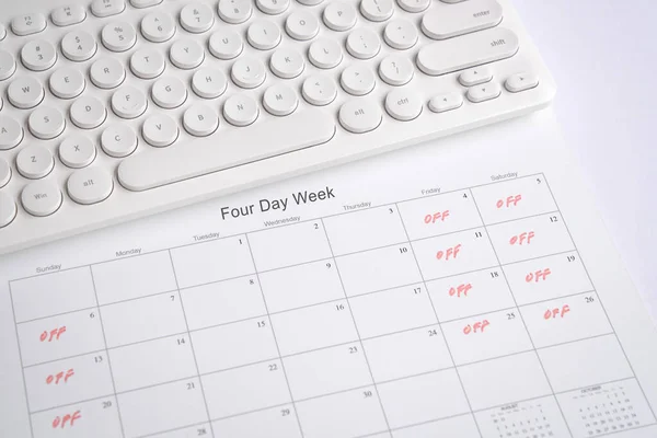 Haftanın dört günü iş takvimi, cuma, cumartesi ve pazar günleri tatil. Klavyeli ofis masası.