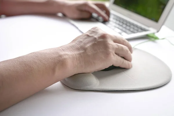 Adamın parmakları fareye tıkırdıyor, bileğini bileğinde dinlendiriyor. Yakın çekim..