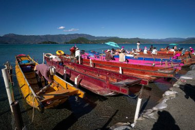 Lijiang, Çin - 15 Ekim 2025: Mosuo halkının renkli tur botlarıyla Lugu Gölü Sahnesi.