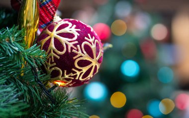Ağaçta asılı renkli bokeh arkaplanlı Noel süsü.