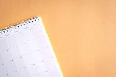 Masa takvimi açık turuncu yüzeyin üzerinde düz duruyor. Boşluğu kopyala.