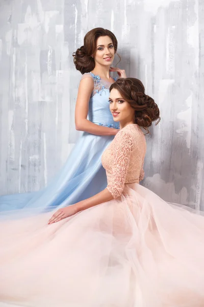 Two beautiful twins young women in luxury dresses, pastel colors. Beauty fashion portrait — Stock Photo, Image