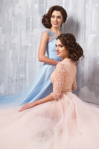 Two beautiful twins young women in luxury dresses, pastel colors. Beauty fashion portrait — Stock Photo, Image