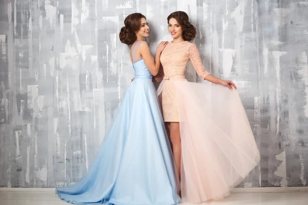 Dos hermosas gemelas mujeres jóvenes en vestidos de lujo, colores pastel. Retrato de moda de belleza —  Fotos de Stock