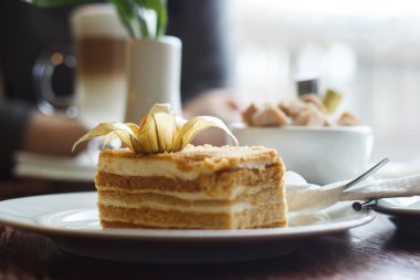 Şehrin bulanık arka plan üzerinde bir kafede kek, şeker kase ve latte kahve fincan parçası