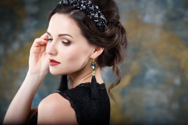 Mükemmel makyaj ve saç stili diadem ve küpeler ile siyah elbiseli olan zarif kadın. Güzellik moda portre aksesuarları ile