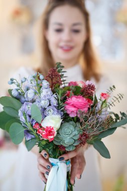 genç kadın yapmış bir buket tutar. Bir masaya çiçek kompozisyon ve dekor.