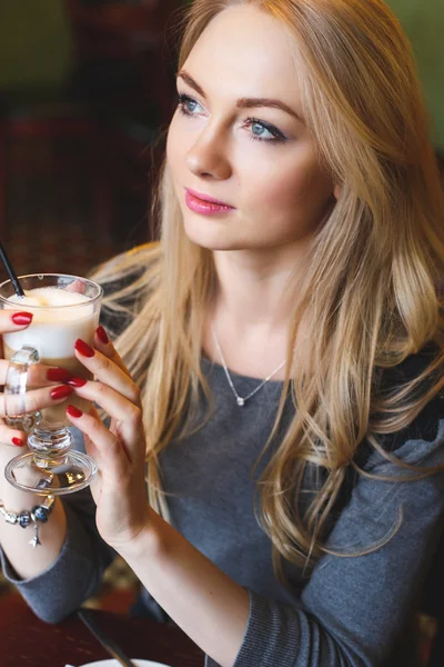 漂亮的金发年轻女子在咖啡馆与一杯拿铁 — 图库照片