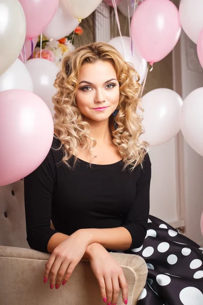 Beautiful curly young woman in a room with many pink and white air balloons. Beauty fashion portrait — Stock Photo, Image