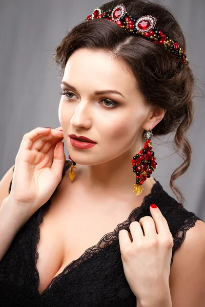 Elegante junge Frau mit perfektem Make-up und perfekter Frisur in einem schwarzen Kleid mit Diadem und Ohrringen. Beauty Fashion Portrait mit Accessoires — Stockfoto