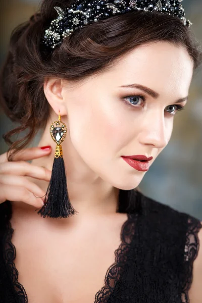 Elegante junge Frau mit perfektem Make-up und perfekter Frisur in einem schwarzen Kleid mit Diadem und Ohrringen. Beauty Fashion Portrait mit Accessoires — Stockfoto