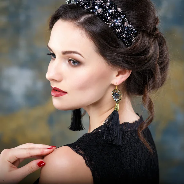 Elegante junge Frau mit perfektem Make-up und perfekter Frisur in einem schwarzen Kleid mit Diadem und Ohrringen. Beauty Fashion Portrait mit Accessoires — Stockfoto