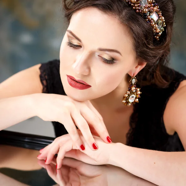 Elegante junge Frau mit perfektem Make-up und perfekter Frisur in einem schwarzen Kleid mit Diadem und Ohrringen. Beauty Fashion Portrait mit Accessoires — Stockfoto