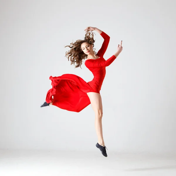 Dancing lady in a red dress. Contemporary modern dance on a white