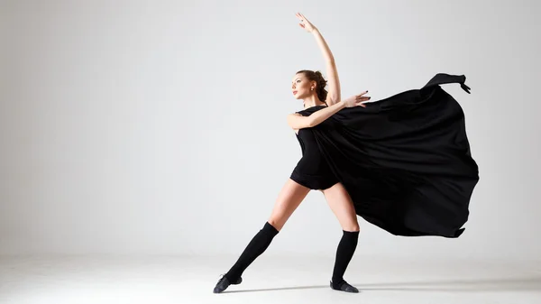 Uma dançarina vestida de preto. Dança moderna contemporânea sobre um fundo branco isolado. Fitness, modelo de alongamento — Fotografia de Stock