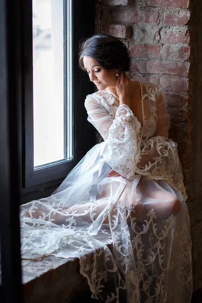 Bride's morning in a loft. Beautiful brunette young woman in a white negligee in a morning — Stock Photo, Image