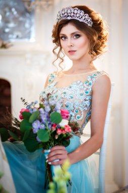 Bir buket çiçek ile bir tablo başına oturmuş bir lüks mavi elbiseli güzel genç bayan